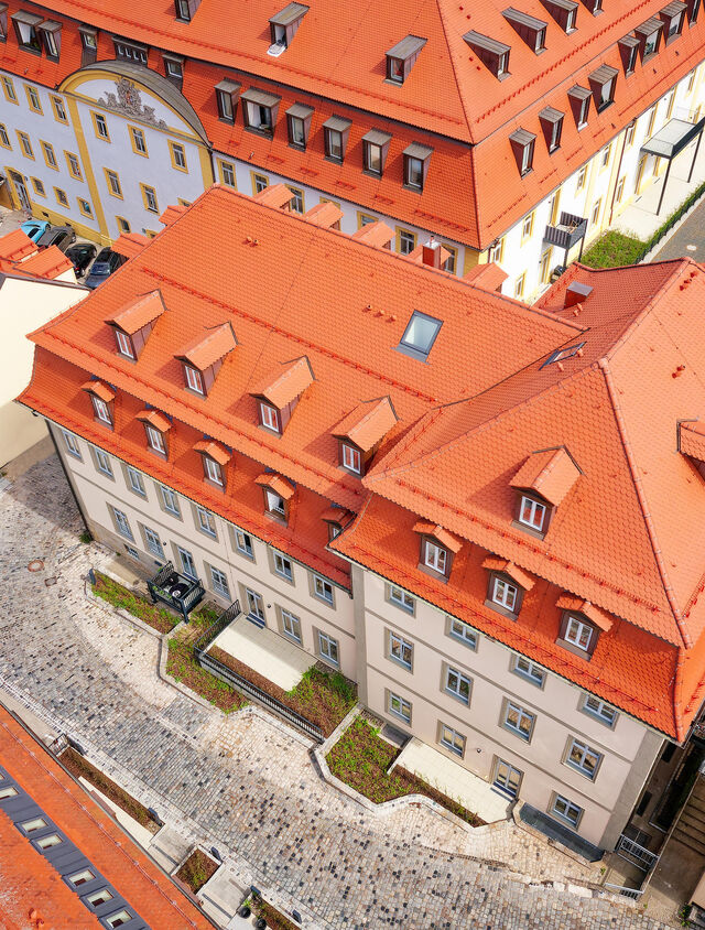 Drohnen-Luftaufnahme saniertes Karmelitenkloster-Geb&auml;ude mit rotem Ziegeldach, Dachgauben und Kopfsteinpflaster-Innenhof im historischen Bamberg