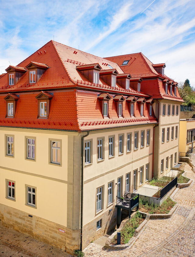 Weite Luftaufnahme saniertes Karmelitenkloster Bamberg mit roten Ziegeld&auml;chern, cremefarbenen Fassaden, Dachgauben und Kopfsteinpflaster-Innenhof im Denkmalensemble