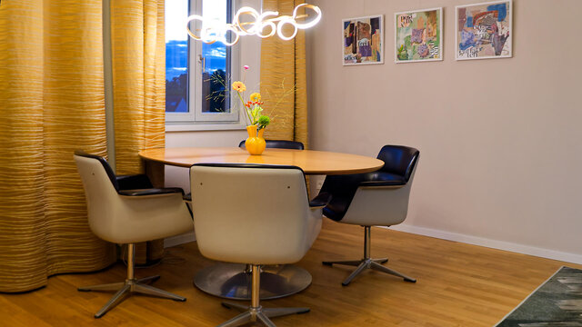Heller Essbereich mit Pierre Paulin Designer-Tisch, Friso Kramer Drehst&uuml;hlen, goldenen Vorh&auml;ngen und Blick auf rote Ziegeld&auml;cher im m&ouml;blierten Premium-Apartment Bamberg Karmelitenkloster