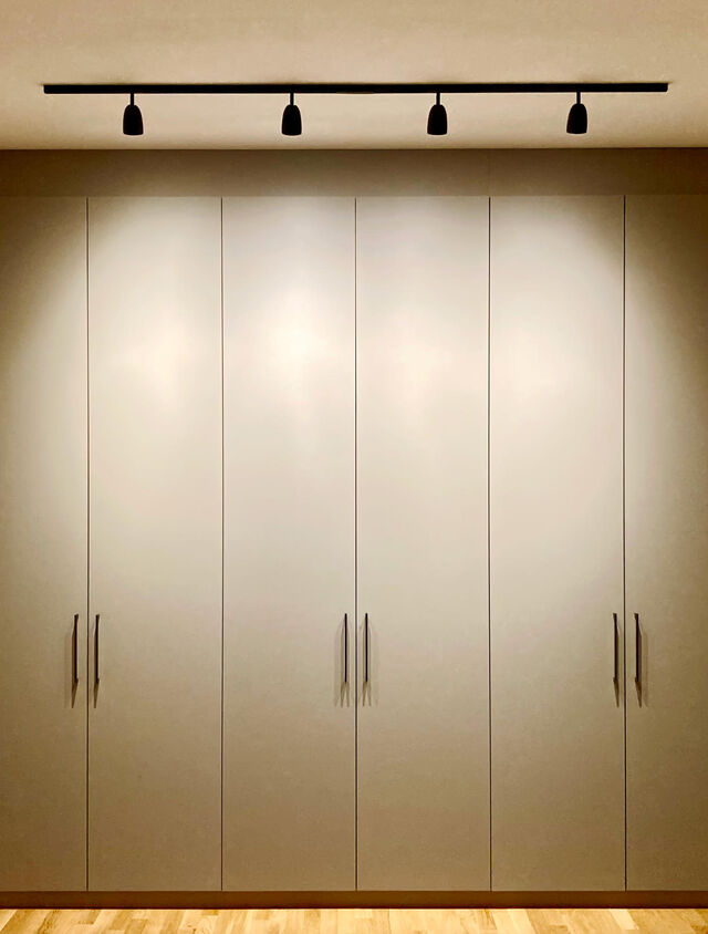 Gro&szlig;er ma&szlig;gefertigter Einbauschrank in hellem Beige mit Metallgriffen, moderner schwarzer Schienenstrahler-Beleuchtung und ornamentalem Goldspiegel im Schlafzimmer-Flur auf Eichenparkett im m&ouml;blierten Apartment Bamberg