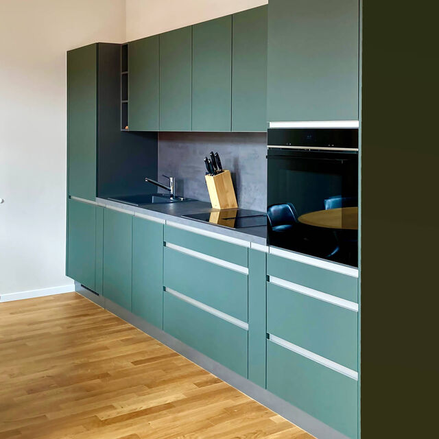 Moderne Nobilia-K&uuml;che in Mineralgr&uuml;n ultramatt mit pflegeleichter Easytouch-Oberfl&auml;che, Aluminium-Griffen und Kanten, integriertem Siemens-Backofen auf Eichenparkett im m&ouml;blierten Apartment Bamberg