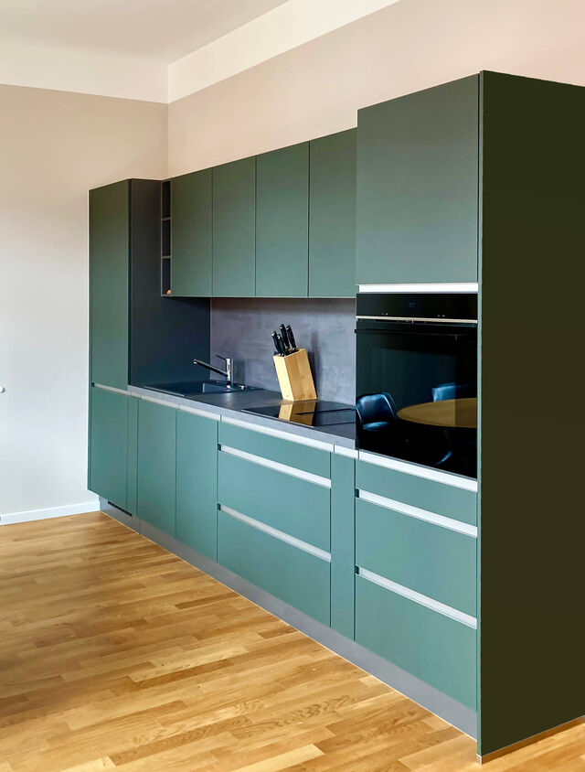 Moderne Nobilia-K&uuml;che in Mineralgr&uuml;n ultramatt mit pflegeleichter Easytouch-Oberfl&auml;che, Aluminium-Griffen und Kanten, integriertem Siemens-Backofen auf Eichenparkett im m&ouml;blierten Apartment Bamberg