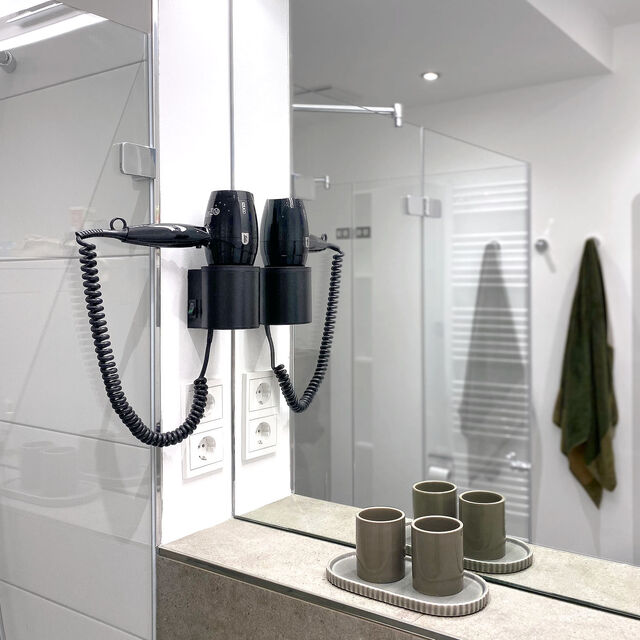 Moderner Badspiegel mit LED-Beleuchtung, wandmontiertem F&ouml;hn und elegantem Keramik-Bad-Accessoire-Set im m&ouml;blierten Apartment Bamberg